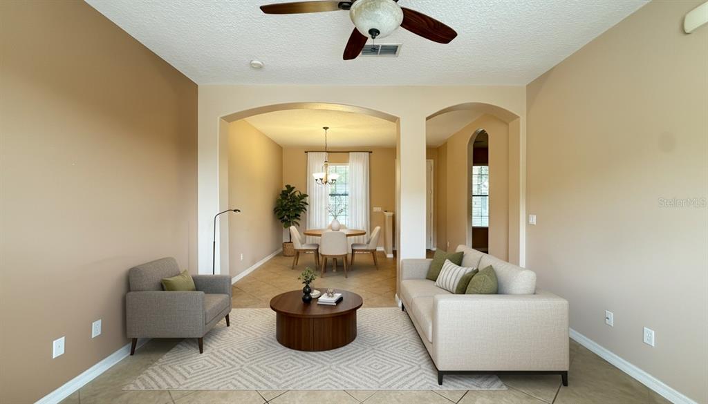 A living room and dining area with tile floors, neutral walls, and a ceiling fan — 13851 BEAUREGARD PLACE, ORLANDO, FL