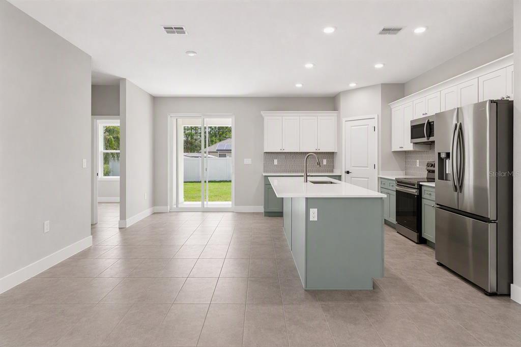 A modern kitchen with a large island, white cabinets, and stainless steel appliances — 191 UNDERWOOD TRAIL, PALM COAST, FL