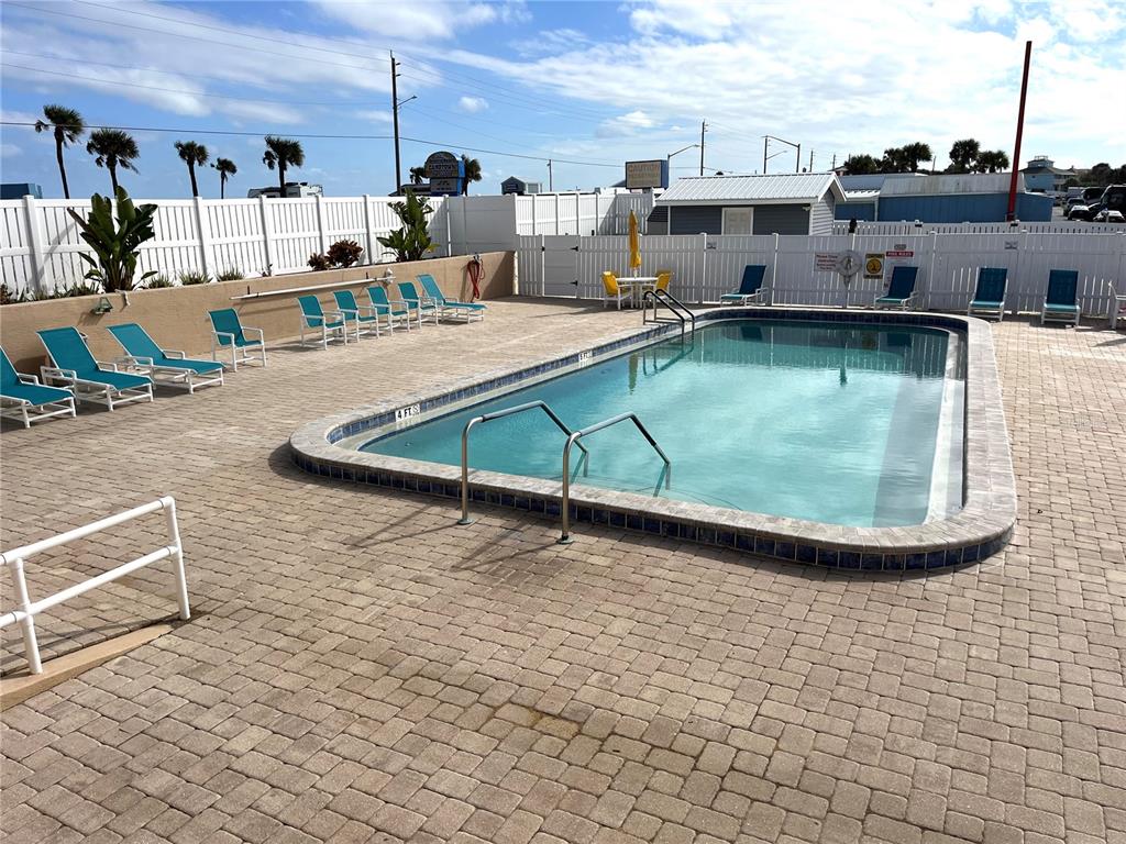 An outdoor swimming pool with lounge chairs on a paved deck surrounded by white fencing — 225 STARBOARD DRIVE, FLAGLER BEACH, FL
