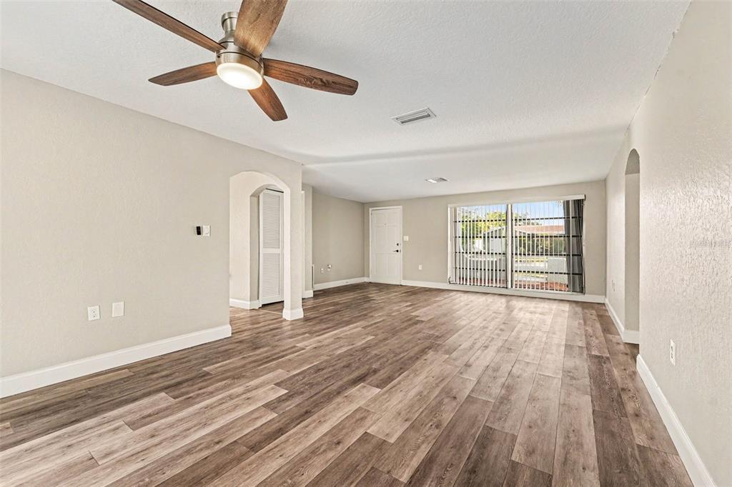 A dining area with wood-look flooring opens into a white kitchen with stainless steel appliances — 3207 SALISBURY DRIVE, HOLIDAY, FL