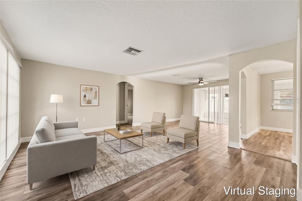 A kitchen features white cabinets, stainless steel appliances, subway tile backsplash, and wood-look flooring — 3207 SALISBURY DRIVE, HOLIDAY, FL