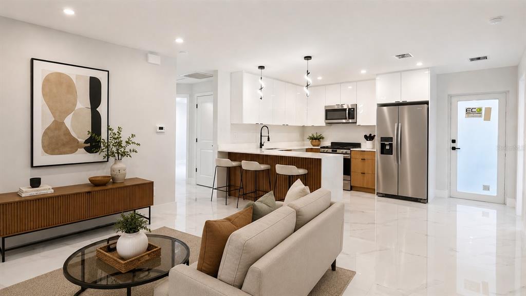 A modern open-concept kitchen and living area features white cabinetry, marble floors, and stainless appliances — 729 ANACONDA AVENUE S, LEHIGH ACRES, FL