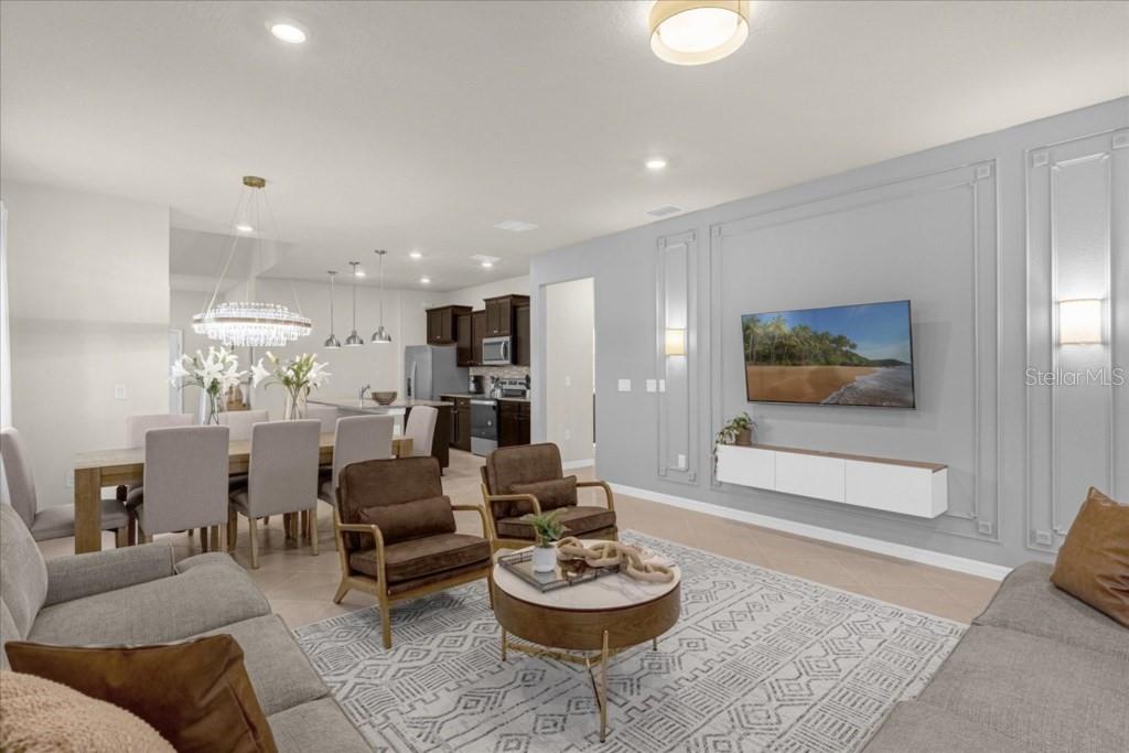 A modern open-concept living and dining area features gray walls, wood flooring, and a chandelier — 1261 EMERALD ROW STREET, CLERMONT, FL