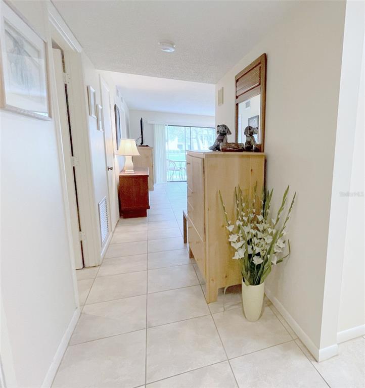 A tiled hallway leads to a living area with a sliding glass door — 4648 LONGWATER CHASE UNIT 99, SARASOTA, FL