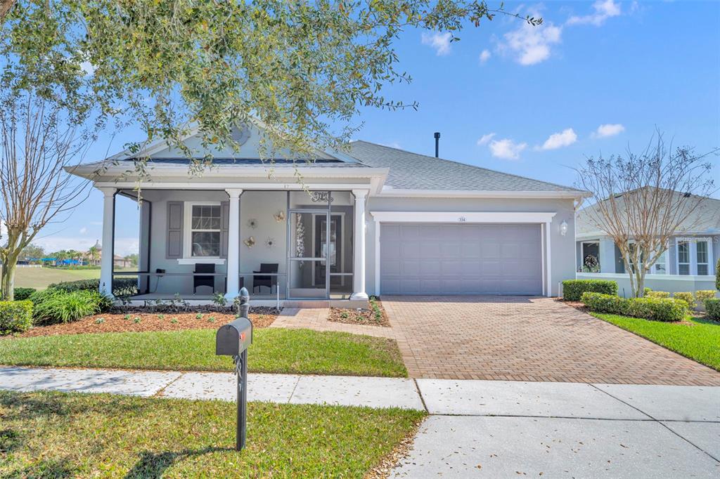 A single-story house with a screened front porch, gray siding, and a brick paver driveway — 334 SILVER MAPLE ROAD, GROVELAND, FL