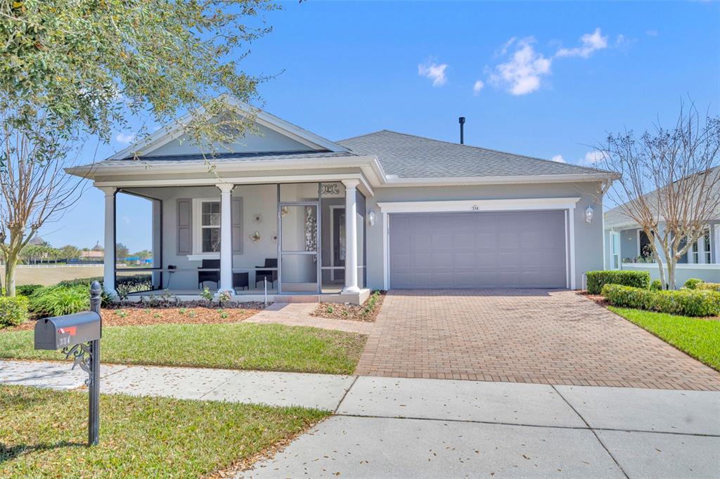 A single-story house with a screened front porch, a two-car garage, and a paved driveway — 334 SILVER MAPLE ROAD, GROVELAND, FL