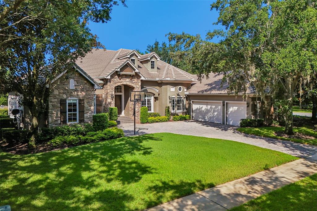 A two-story house with a stone facade, a paved driveway, and a two-car garage — 6102 S HAMPSHIRE CT, WINDERMERE, FL