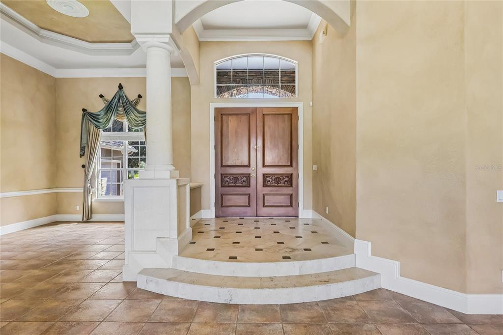 An entryway features a raised tiled landing, double wooden doors, and a decorative column — 6102 S HAMPSHIRE CT, WINDERMERE, FL