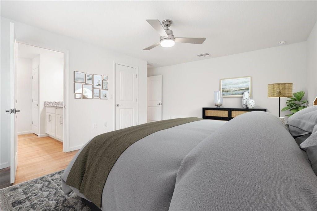 A bedroom features a gray bed, a ceiling fan, and an open doorway to a bathroom — 36 RYMER LANE, PALM COAST, FL