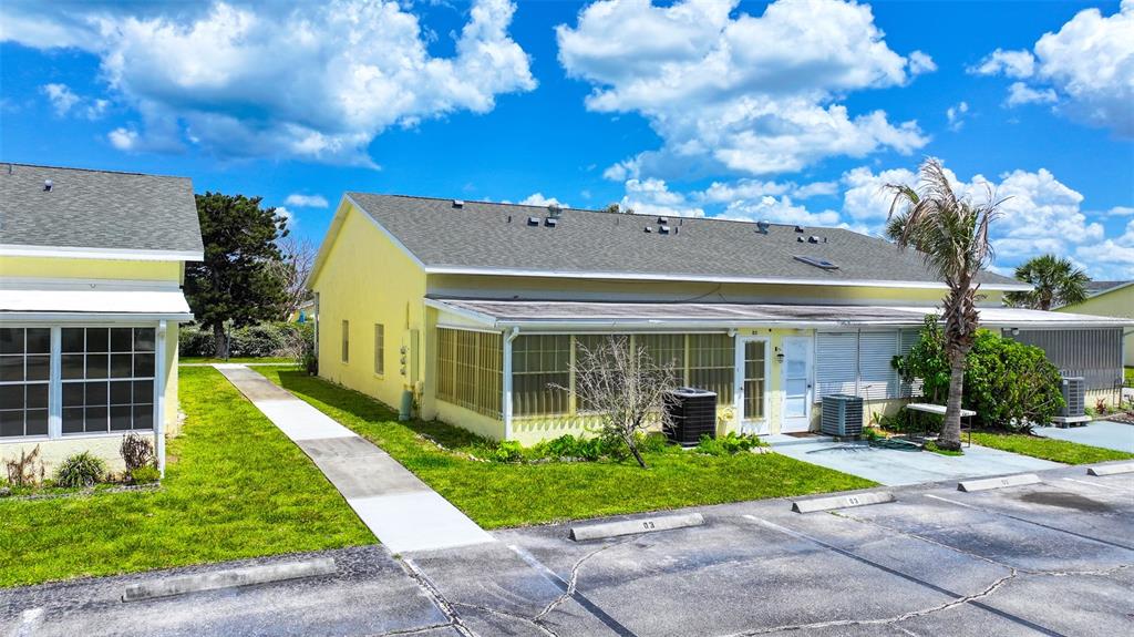 An exterior view of a yellow residential building with a screened-in porch and parking spaces — 8520 US HIGHWAY 1 UNIT D3, MICCO, FL