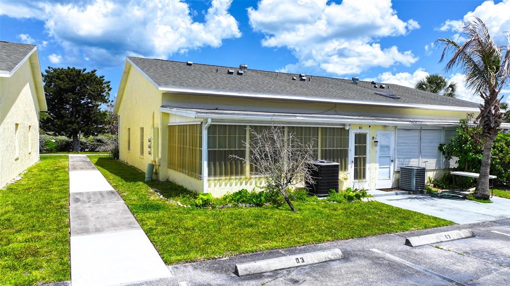 A yellow single-story building features a screened-in porch, a concrete walkway, and assigned parking spaces — 8520 US HIGHWAY 1 UNIT D3, MICCO, FL