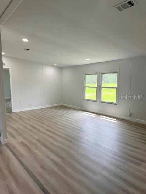An empty room features light wood-look flooring, white walls, recessed lighting, and two large windows — 5118 BENNETT DRIVE, LAKELAND, FL