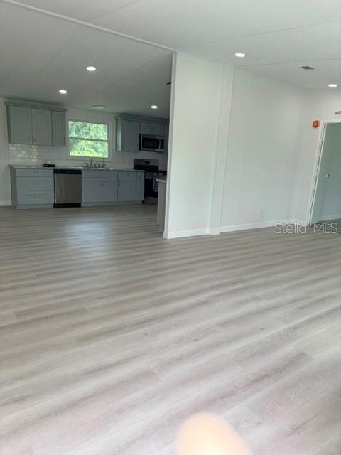 A kitchen with light gray cabinets and stainless steel appliances opens into a living area — 5118 BENNETT DRIVE, LAKELAND, FL
