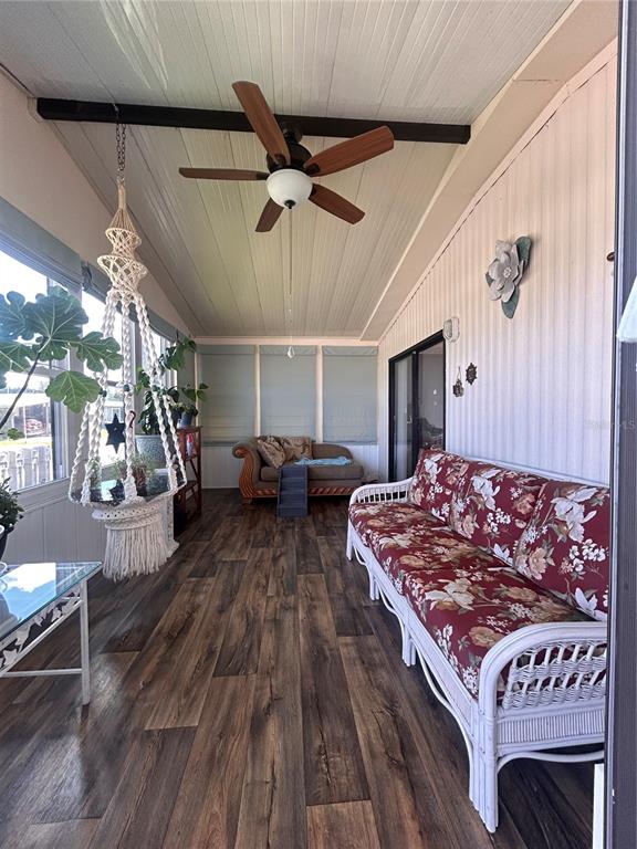 A sunroom features wood-look flooring, a ceiling fan, a floral sofa, and a macramé hanging chair — 6458 HOLLYBERRY LANE NE, WINTER HAVEN, FL