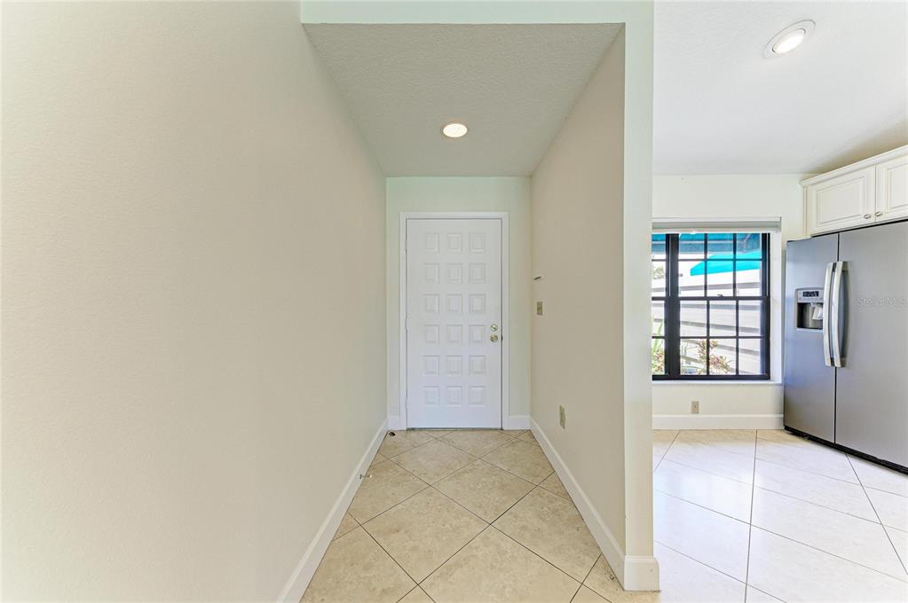 A tiled entryway leads to a white front door next to a kitchen with appliances — 6085 CLUBSIDE DRIVE, SARASOTA, FL