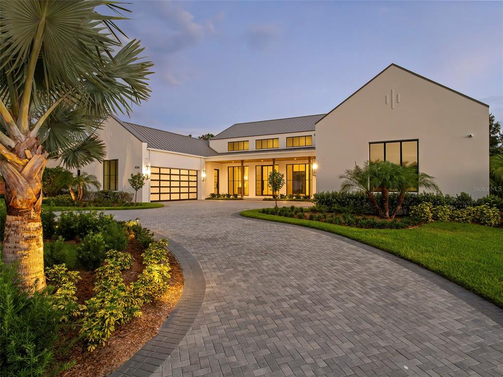 A modern house with a metal roof, white stucco exterior, and a paved circular driveway — 9316 GLADYS GARDEN CT, WINDERMERE, FL