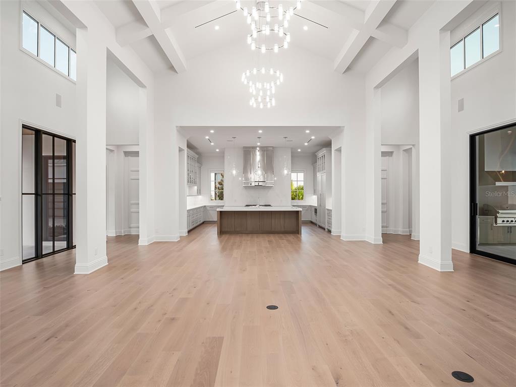 A spacious, high-ceilinged kitchen and living area features light wood floors and white walls — 9316 GLADYS GARDEN CT, WINDERMERE, FL
