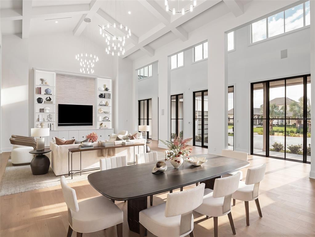 A bright, open-concept living and dining area features high vaulted ceilings, white walls, and large windows — 9316 GLADYS GARDEN CT, WINDERMERE, FL