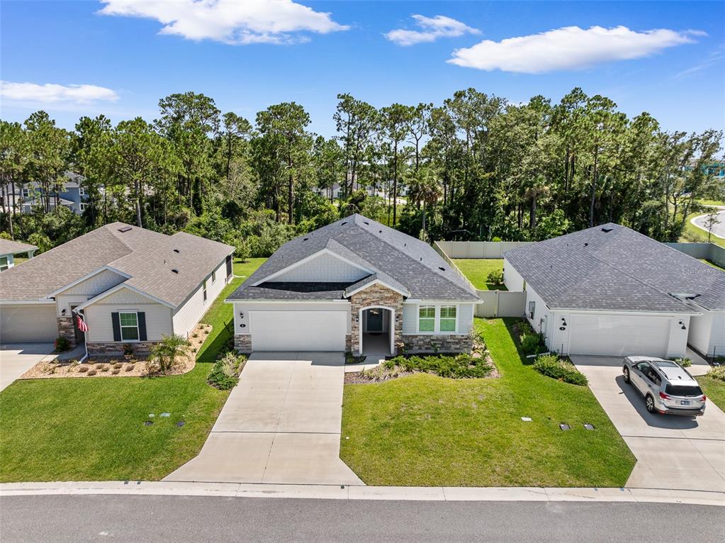 An aerial view shows three suburban houses with driveways and lawns against a treeline — 6 SIGNET CIRCLE, FLAGLER BEACH, FL