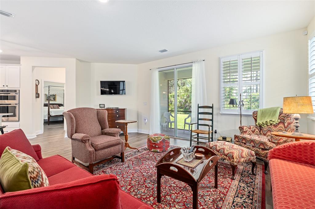 A living room features a red sofa, patterned armchairs, a large rug, and sliding glass doors — 6 SIGNET CIRCLE, FLAGLER BEACH, FL