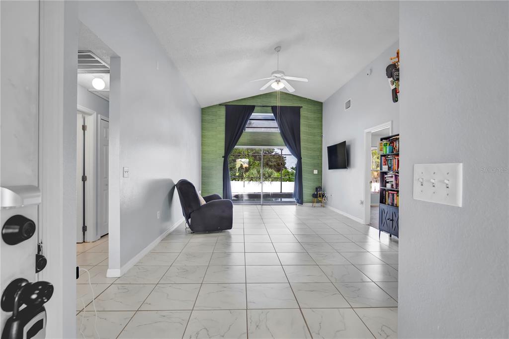 A living room features white tile floors, a vaulted ceiling, and a green accent wall — 324 CASTERTON CIRCLE, DAVENPORT, FL