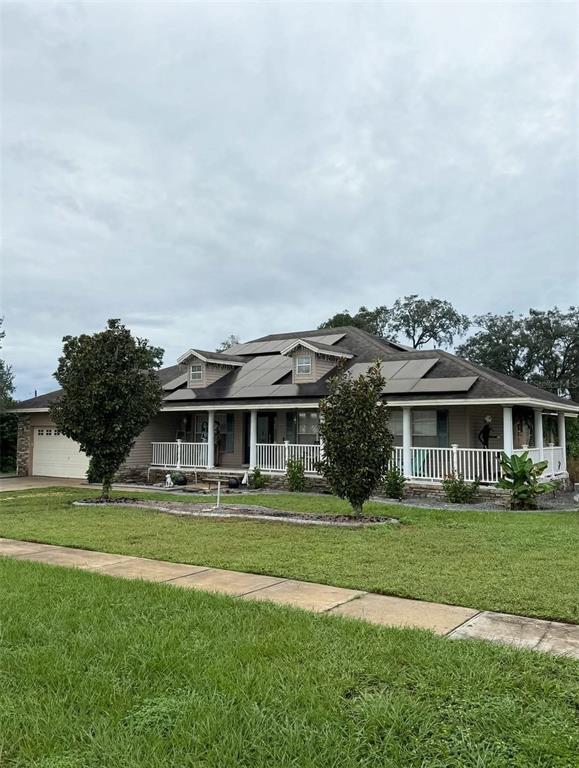 A single-story house with a concrete driveway, a covered porch, and a large front lawn — 12 E LEMON STREET, DAVENPORT, FL