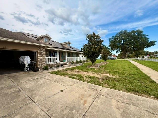 A single-story house with a concrete driveway, a covered porch, and a large front lawn — 12 E LEMON STREET, DAVENPORT, FL