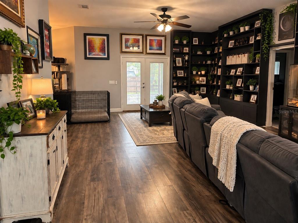 A living room features a large built-in bookshelf, a reptile enclosure, and a gray sectional sofa — 12 E LEMON STREET, DAVENPORT, FL