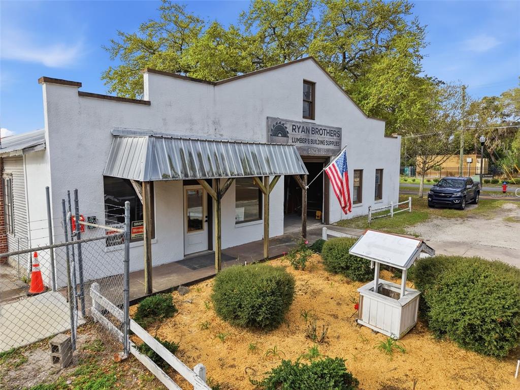An exterior view of a white commercial building with a metal awning and a wishing well — 210 5TH STREET, APOPKA, FL