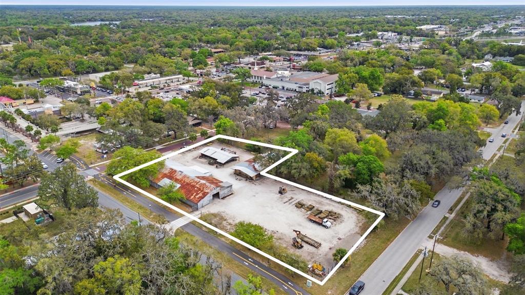 An aerial view shows a fenced industrial lot with several metal-roofed buildings and equipment — 210 5TH STREET, APOPKA, FL