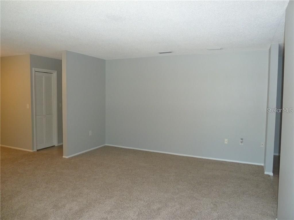 An empty room with gray walls, beige carpet, and a white louvered closet door — 212 CARYL WAY UNIT 212, OLDSMAR, FL