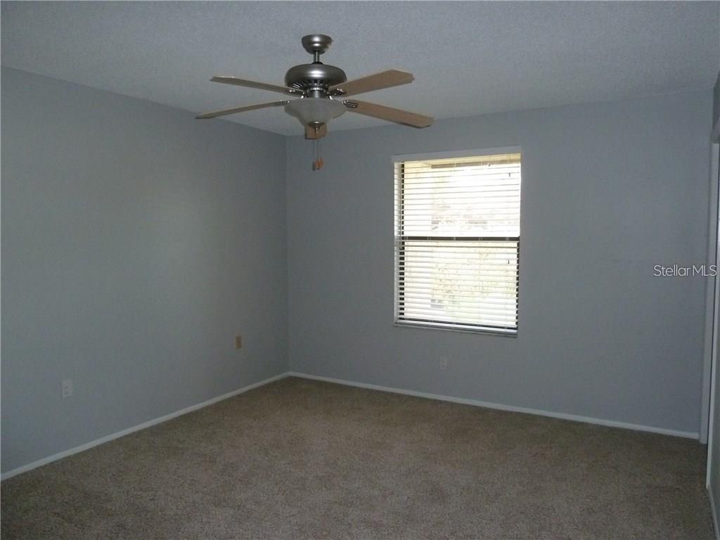 An empty bedroom features gray walls, beige carpeting, a ceiling fan, and a window — 212 CARYL WAY UNIT 212, OLDSMAR, FL