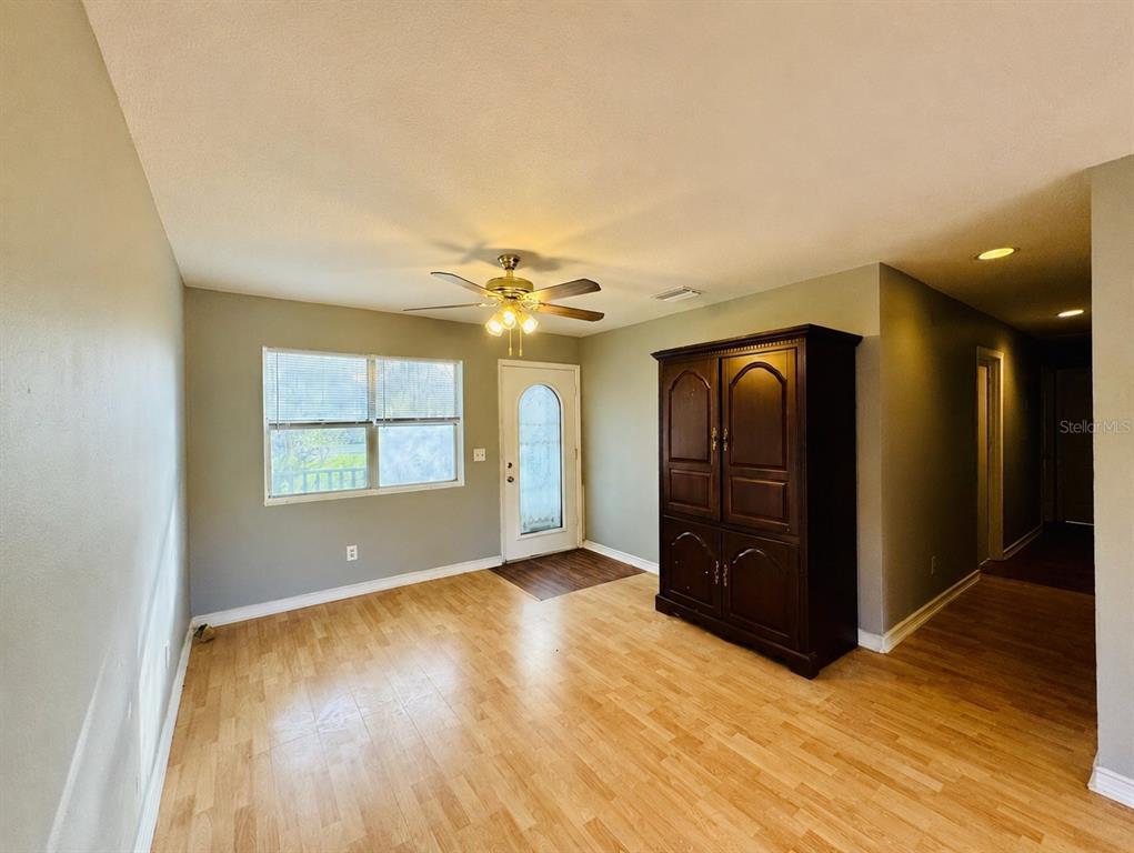 A room with light wood flooring, gray walls, a ceiling fan, and a large armoire — 12909 LITEWOOD DRIVE, HUDSON, FL