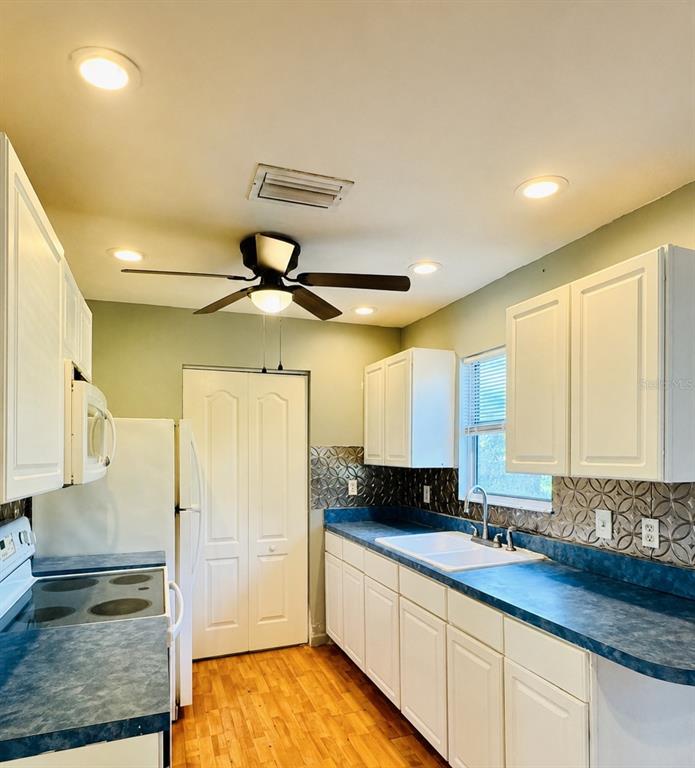 A kitchen features white cabinets, blue countertops, a ceiling fan, and a double-door pantry — 12909 LITEWOOD DRIVE, HUDSON, FL