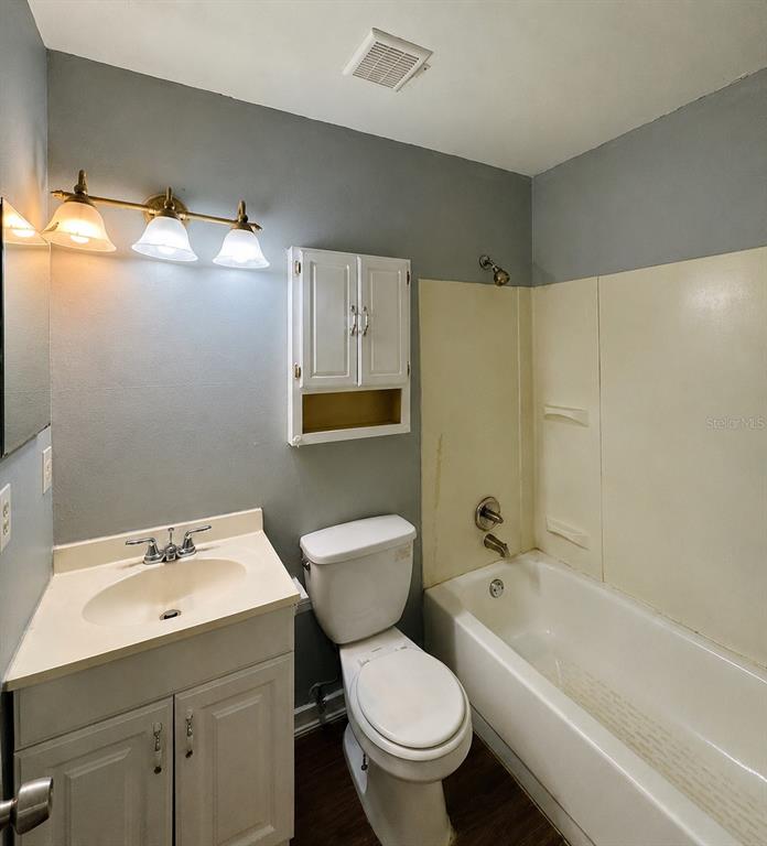 A bathroom features a vanity, toilet, and a shower-tub combination with beige wall panels — 12909 LITEWOOD DRIVE, HUDSON, FL