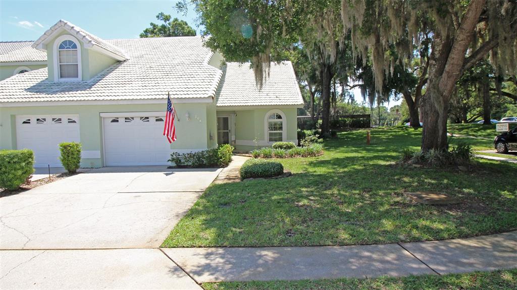 A light green house with a white tile roof, a garage, and a front lawn — 704 MORAY DRIVE, INVERNESS, FL