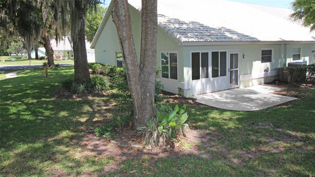 The exterior of a light green house features a white-framed sunroom and a concrete patio — 704 MORAY DRIVE, INVERNESS, FL