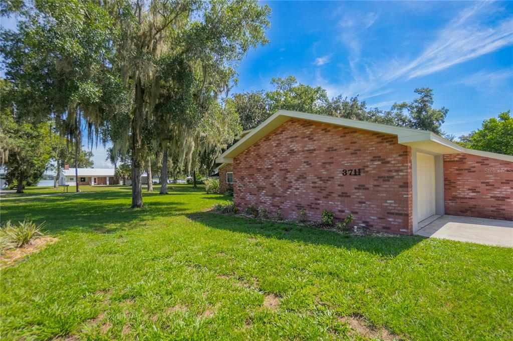 A side view of a brick house with a garage and a large grassy yard — 3711 E TURQUOISE DRIVE, HERNANDO, FL