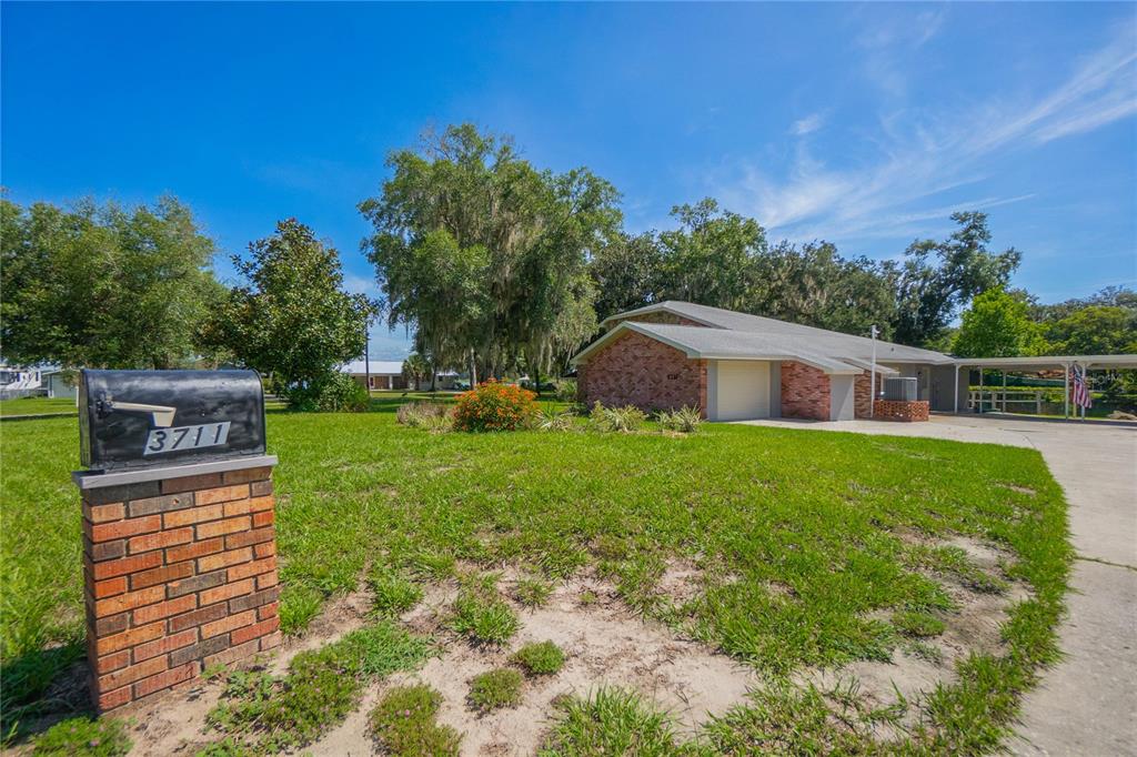 A brick mailbox stands in the foreground of a lawn leading to a brick house — 3711 E TURQUOISE DRIVE, HERNANDO, FL