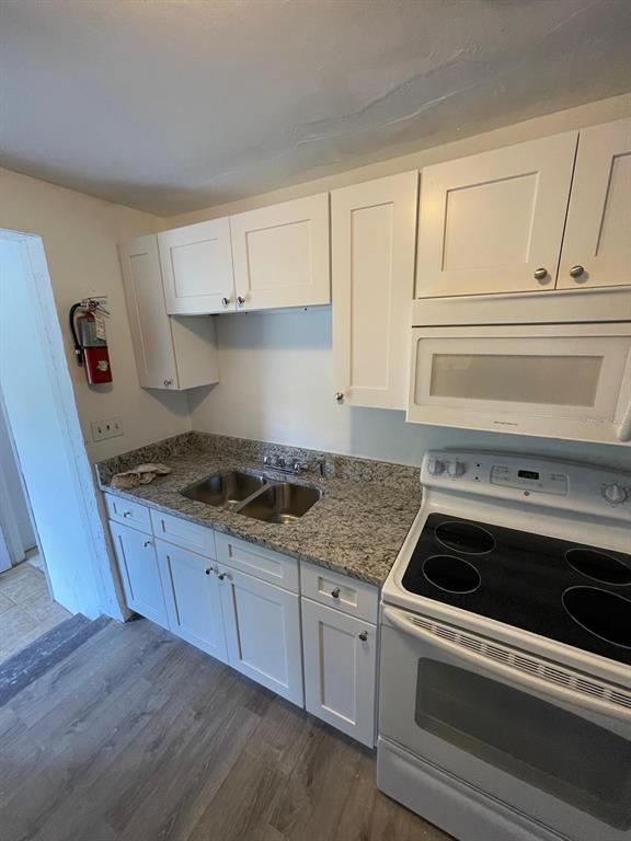 A kitchen features white cabinets, granite countertops, a stainless steel sink, and a white stove — 1142 BERKSHIRE ROAD, DAYTONA BEACH, FL
