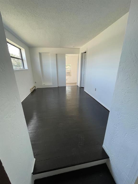 An empty room with dark wood flooring, white walls, and a doorway leading to another room — 1142 BERKSHIRE ROAD, DAYTONA BEACH, FL