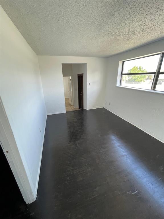 An empty room features dark wood flooring, white walls, and a large window — 1142 BERKSHIRE ROAD, DAYTONA BEACH, FL