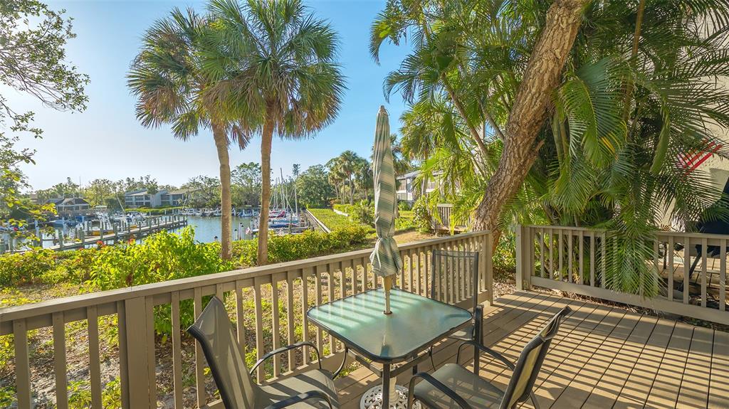 A wooden deck with a patio table and chairs overlooks a marina with docked boats — 1633 BOATHOUSE CIRCLE UNIT HA132, SARASOTA, FL