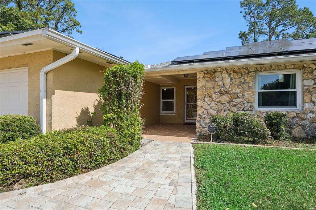 A stone-faced house exterior features a paved walkway leading to a recessed front entryway — 141 FAIRWAY TEN DRIVE, CASSELBERRY, FL