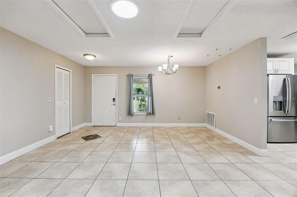 A dining area features beige tile flooring, a chandelier, a window, and a white door — 141 FAIRWAY TEN DRIVE, CASSELBERRY, FL
