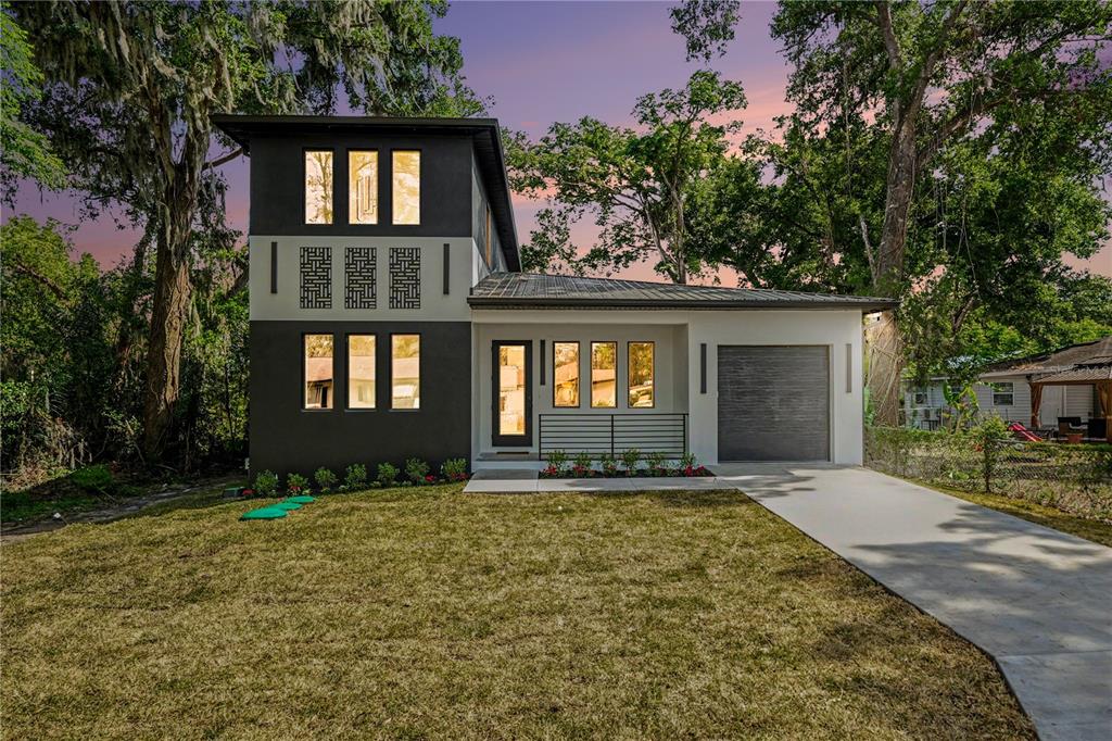 A two-story modern house with a dark gray exterior, white accents, and a concrete driveway — 105 GARLAND AVENUE, SEFFNER, FL