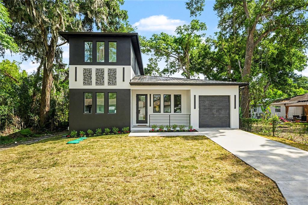 A modern two-story house with a dark gray exterior, white accents, and a concrete driveway — 105 GARLAND AVENUE, SEFFNER, FL