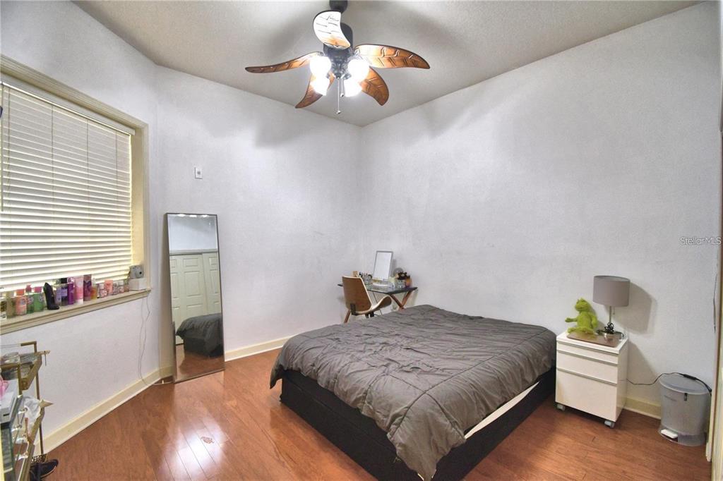 A bedroom with wood flooring, a ceiling fan, a bed, and a floor mirror — 8743 THE ESPLANADE UNIT 8, ORLANDO, FL