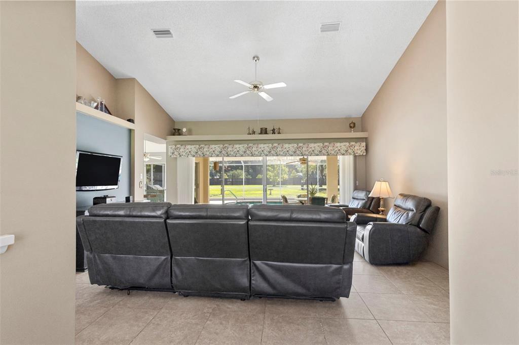 A living room features a large gray sectional sofa, tile flooring, and sliding glass doors — 17269 RAINTREE ROAD, LUTZ, FL