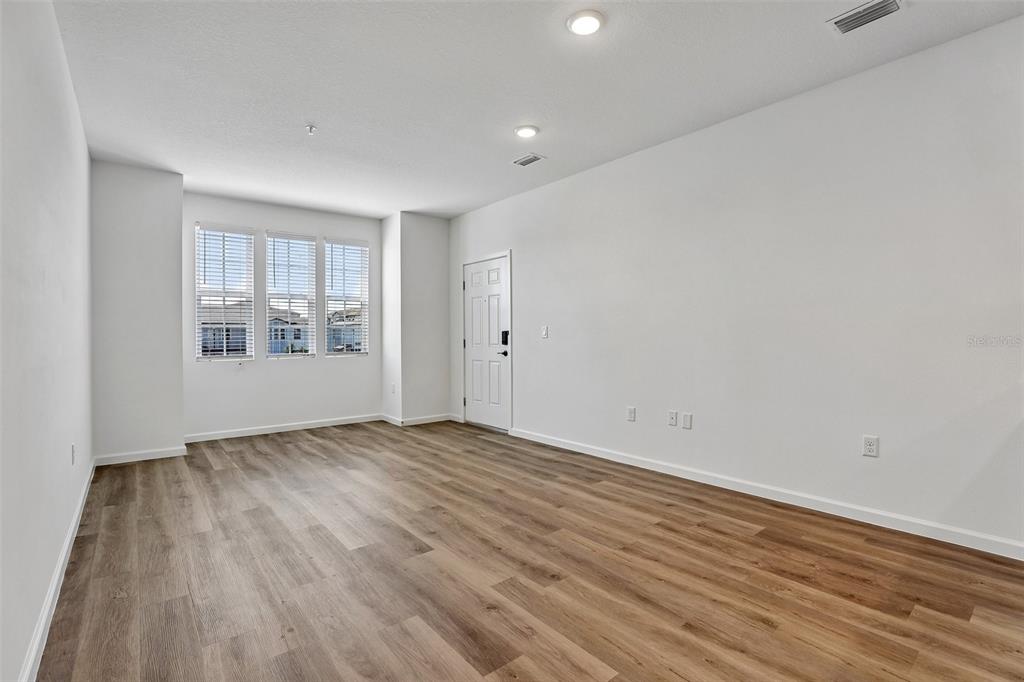 An empty room with white walls, wood-look flooring, recessed lighting, and three windows — 3065 SOLDIER CITY WAY UNIT 201, ST CLOUD, FL